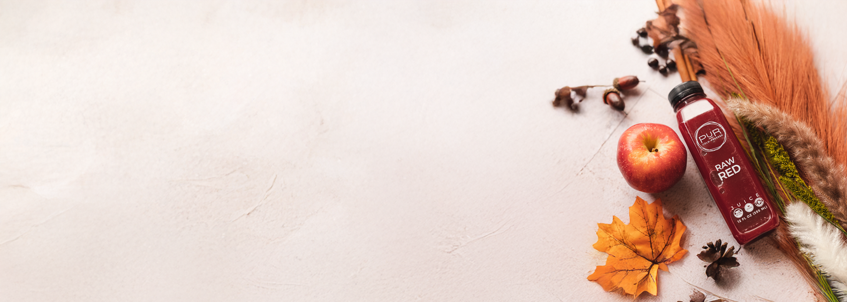 A bottles of 'Raw Red' on a light background with an apple and decorative elements.