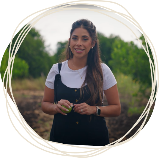 Woman standing outdoors holding a green apple, framed by the PUR Cold-Pressed circular logo design.